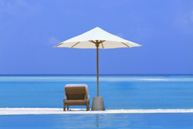 Beach image of blue ocean and chair and umbrella in the foreground
