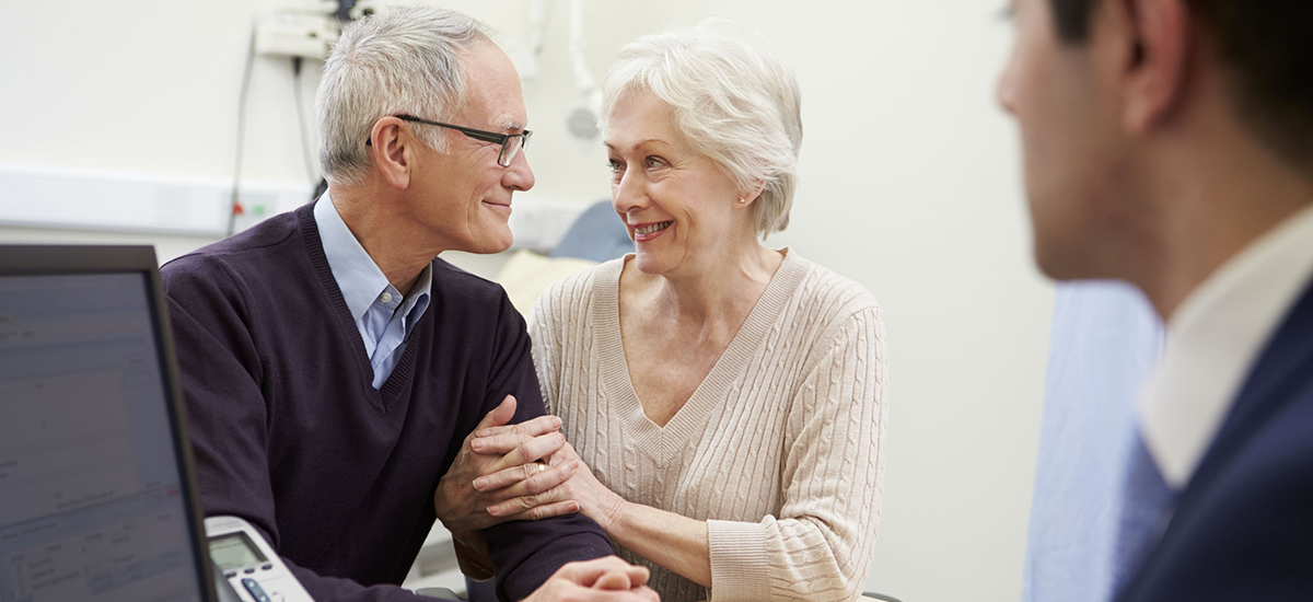 Slide Image of older couple sharing a happy moment with a GP in th econsulting room