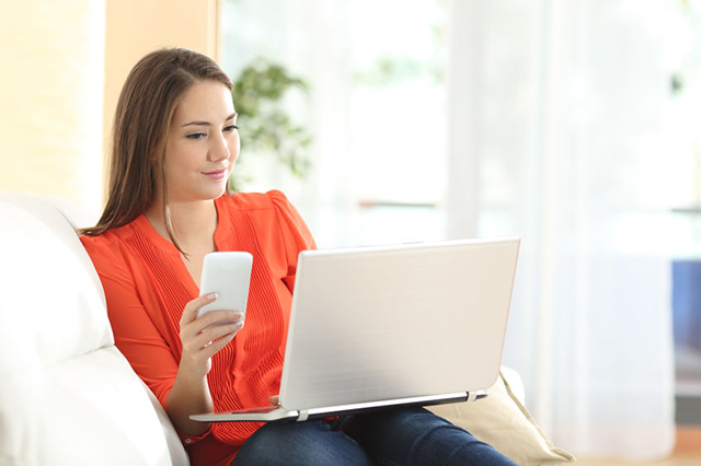 Image of younger patient with laptop and smartphone engaged in video consultation with doctor.